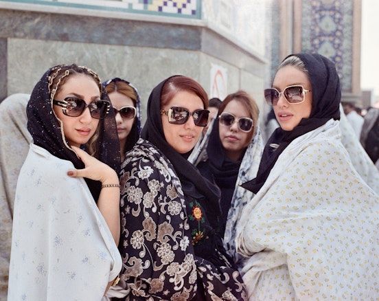 A group of people wearing headscarves and large sunglasses pose for a portrait