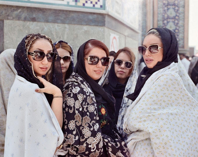 A group of people wearing headscarves and large sunglasses pose for a portrait