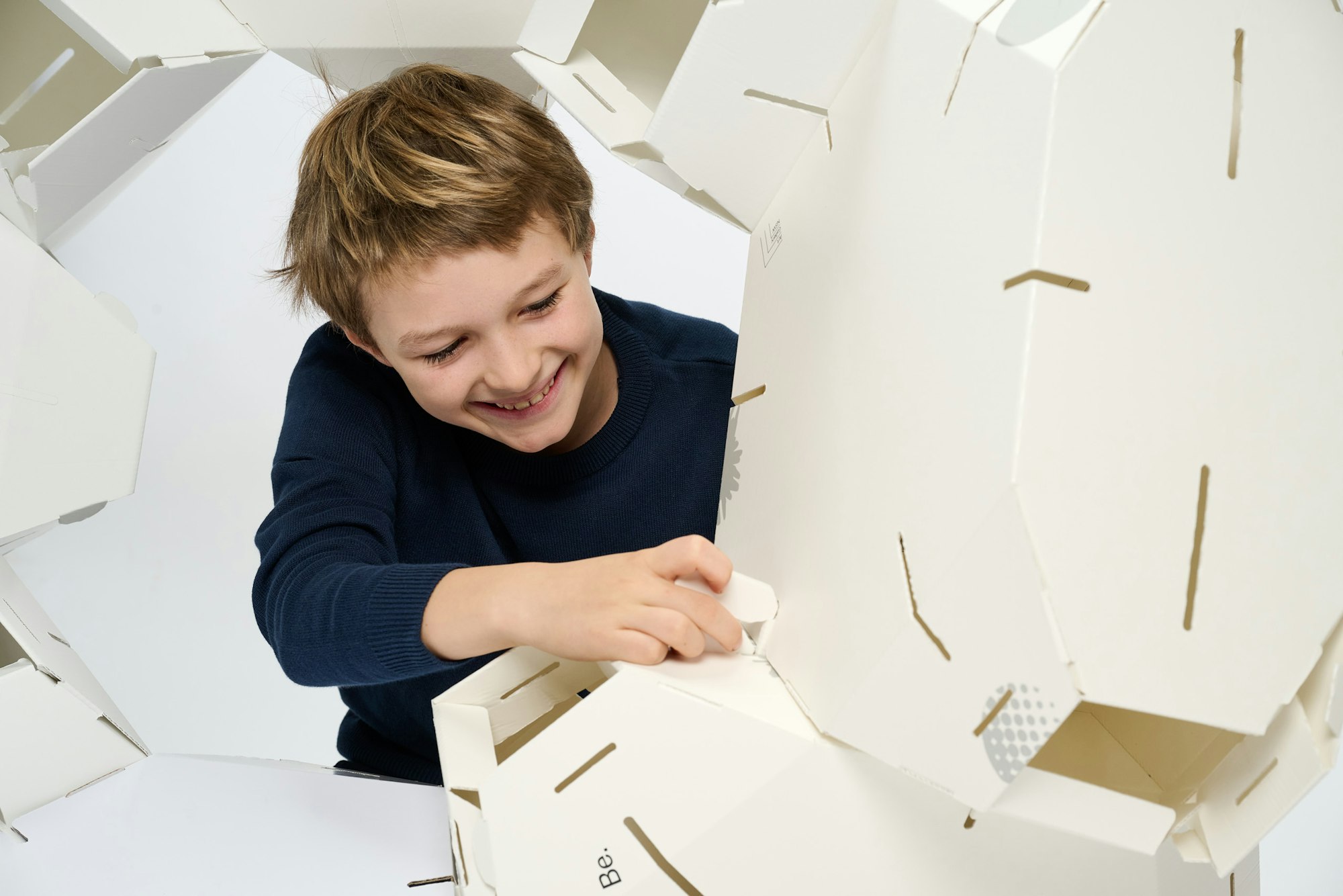 A young person working on a large white cardboard structure