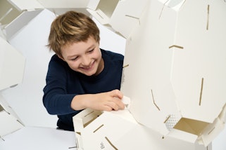 A young person working on a large white cardboard structure