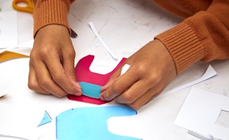 A person's two hands working with pieces of coloured paper
