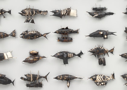 Part of an installation showing four rows of painted metal fish of different kinds