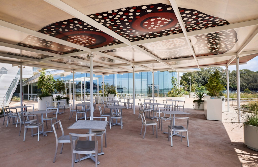 An outdoor eating area with a canopy featuring a painting comprising circular motifs