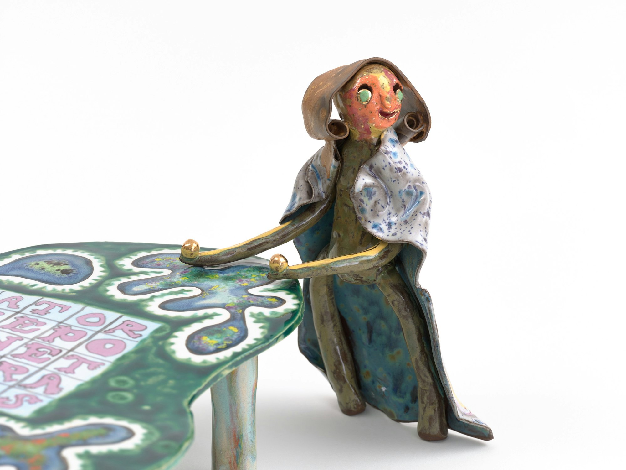 A ceramic figure leans on a ceramic table