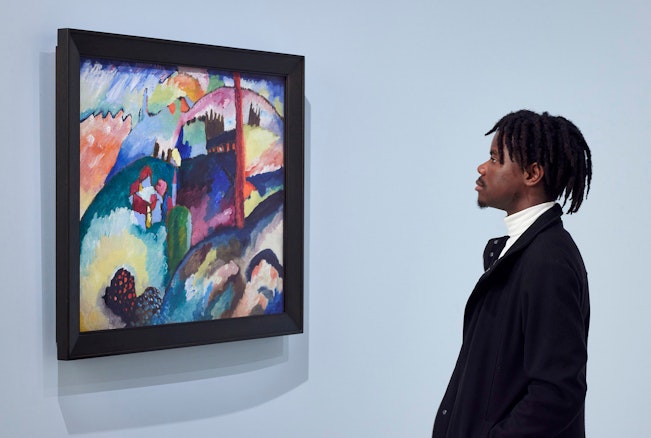 A person looks at a colourful painting on a wall