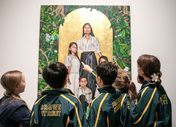 A group of uniformed children stand in front of a group portrait