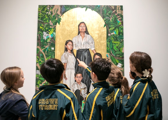 A group of uniformed children stand in front of a group portrait