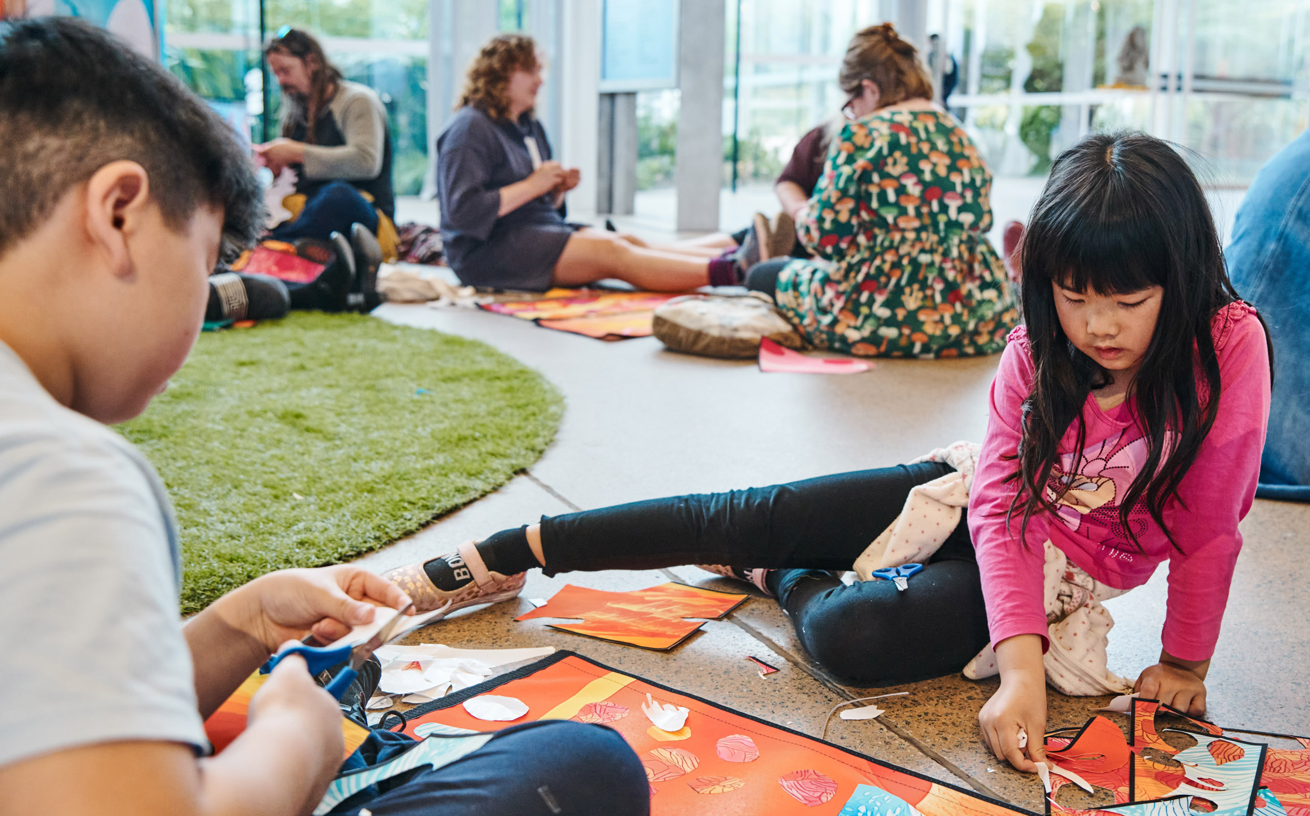 People of different ages sitting on the floor making art