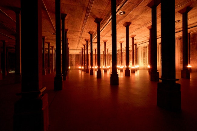 Dark room with tall columns lit dramatically from below.