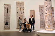Person viewing bark paintings and a sculpture in an art gallery