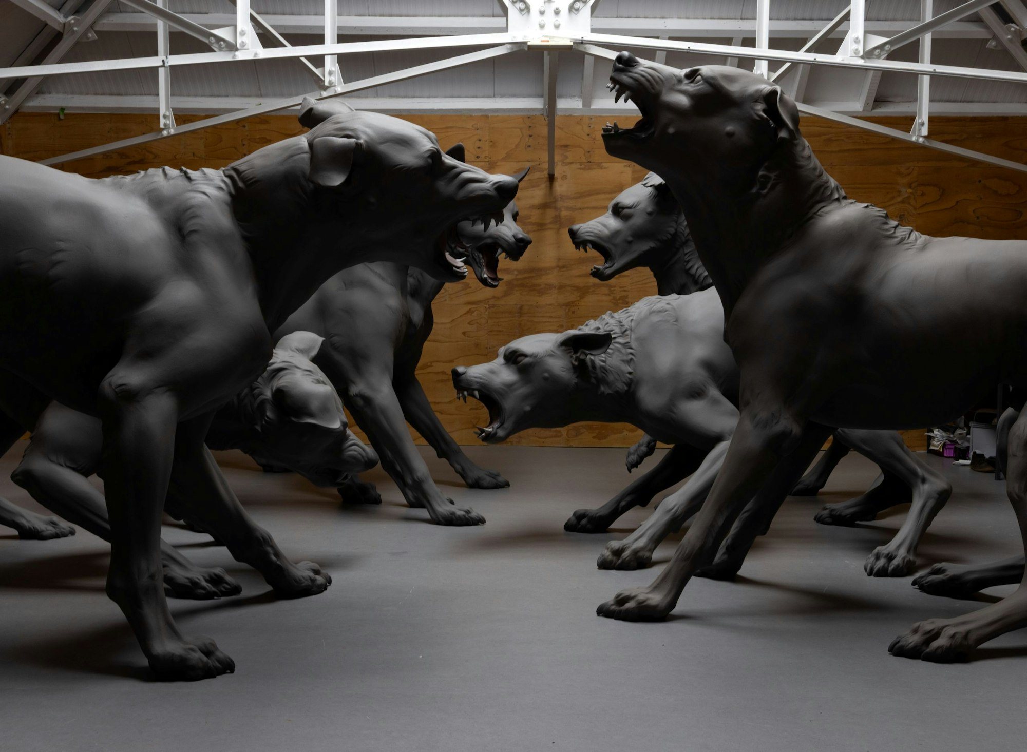 Large dark sculptural works of multiple dogs barking