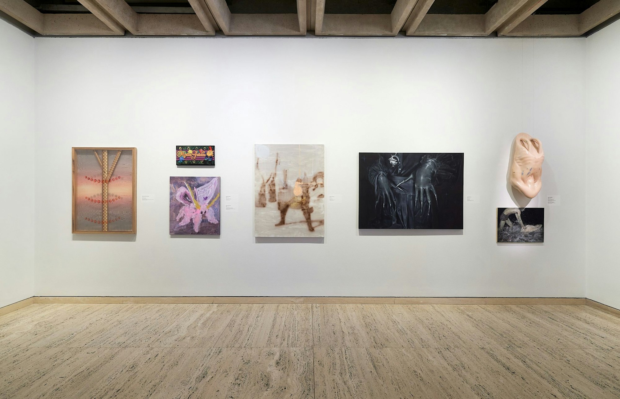 Six paintings and one sculptural item hang up in a gallery space