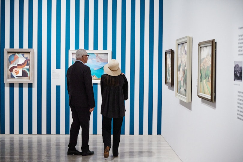 Two visitors viewing paintings in a gallery