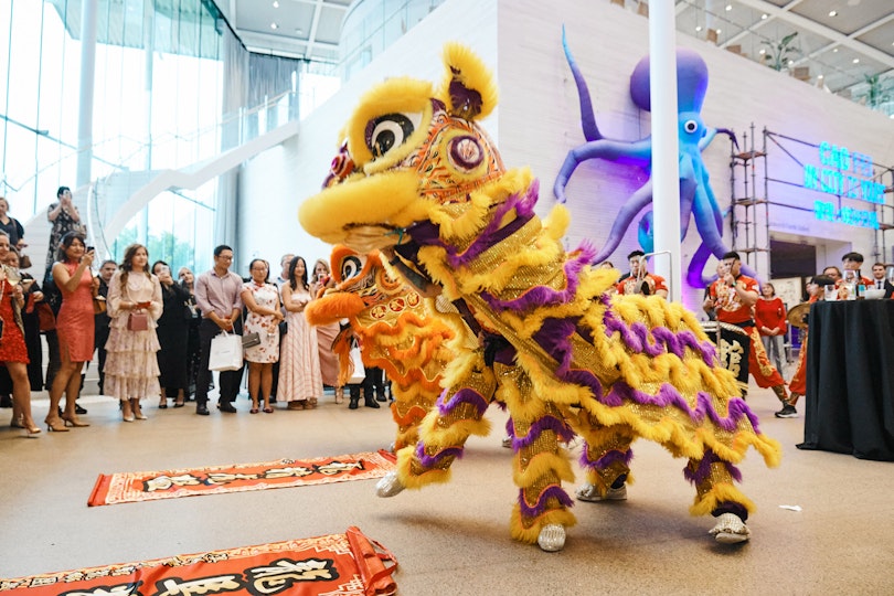 erformers in traditional dragon costumes dancing in a gallery with onlookers