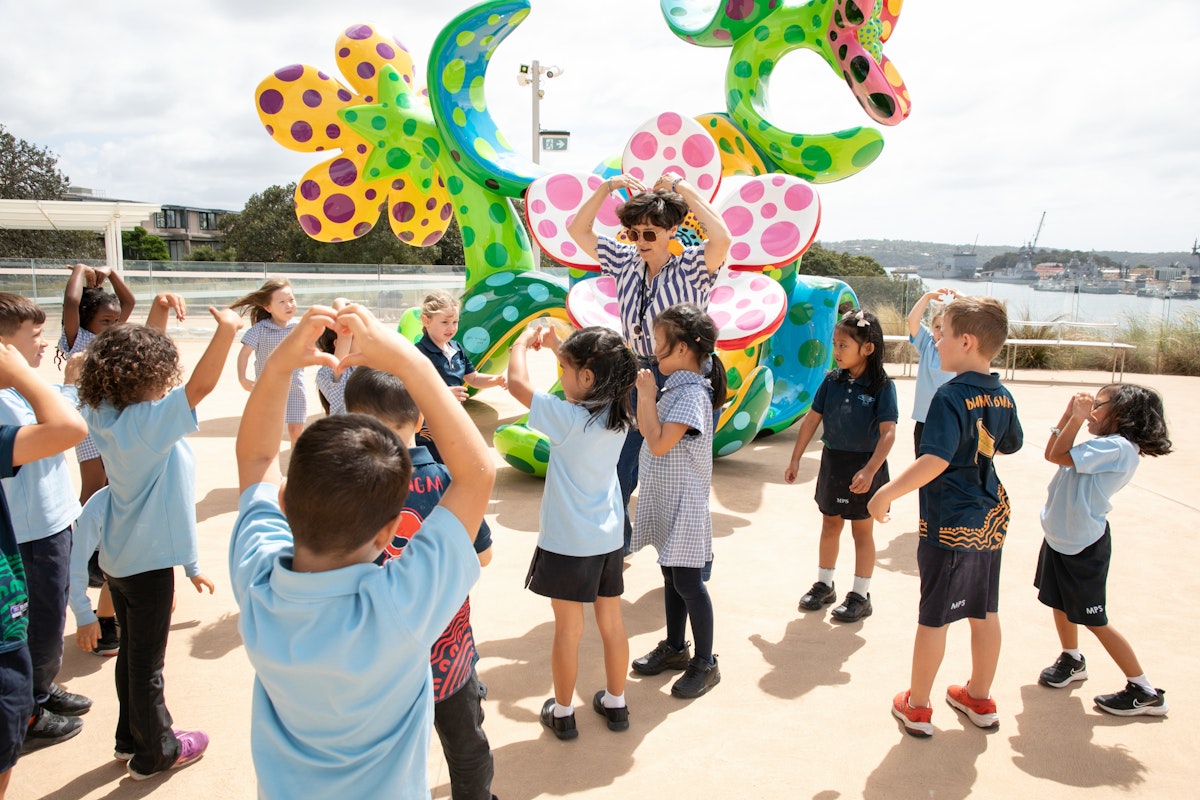 A group of primary school students in front of a sculpture of a bunch of flowers