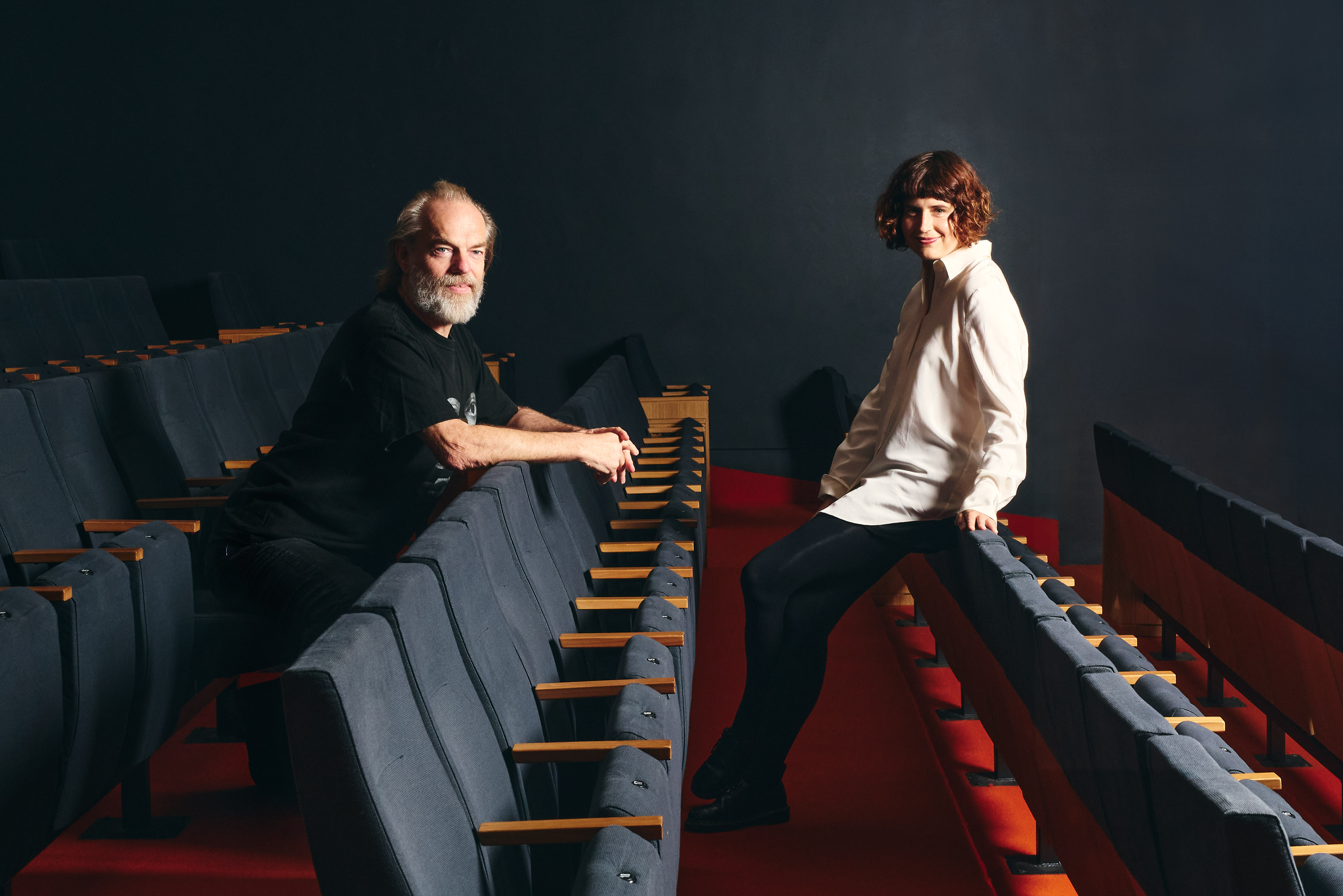 A man and a woman leaning against rows of seats inside a large cinema