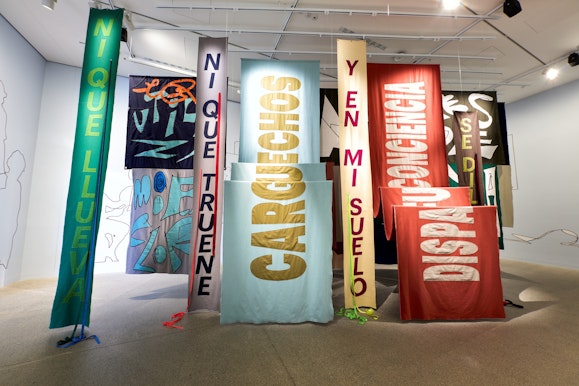Large protest banners hanging vertically in a gallery space.