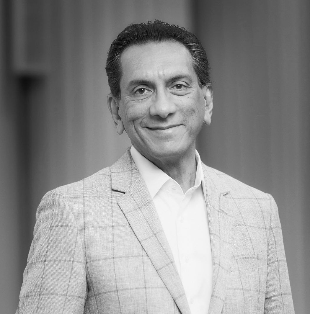 A black and white portrait of a man wearing a suit, smiling at the camera.
