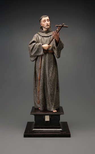 Sculpture of a robed religious figure holding a crucifix.