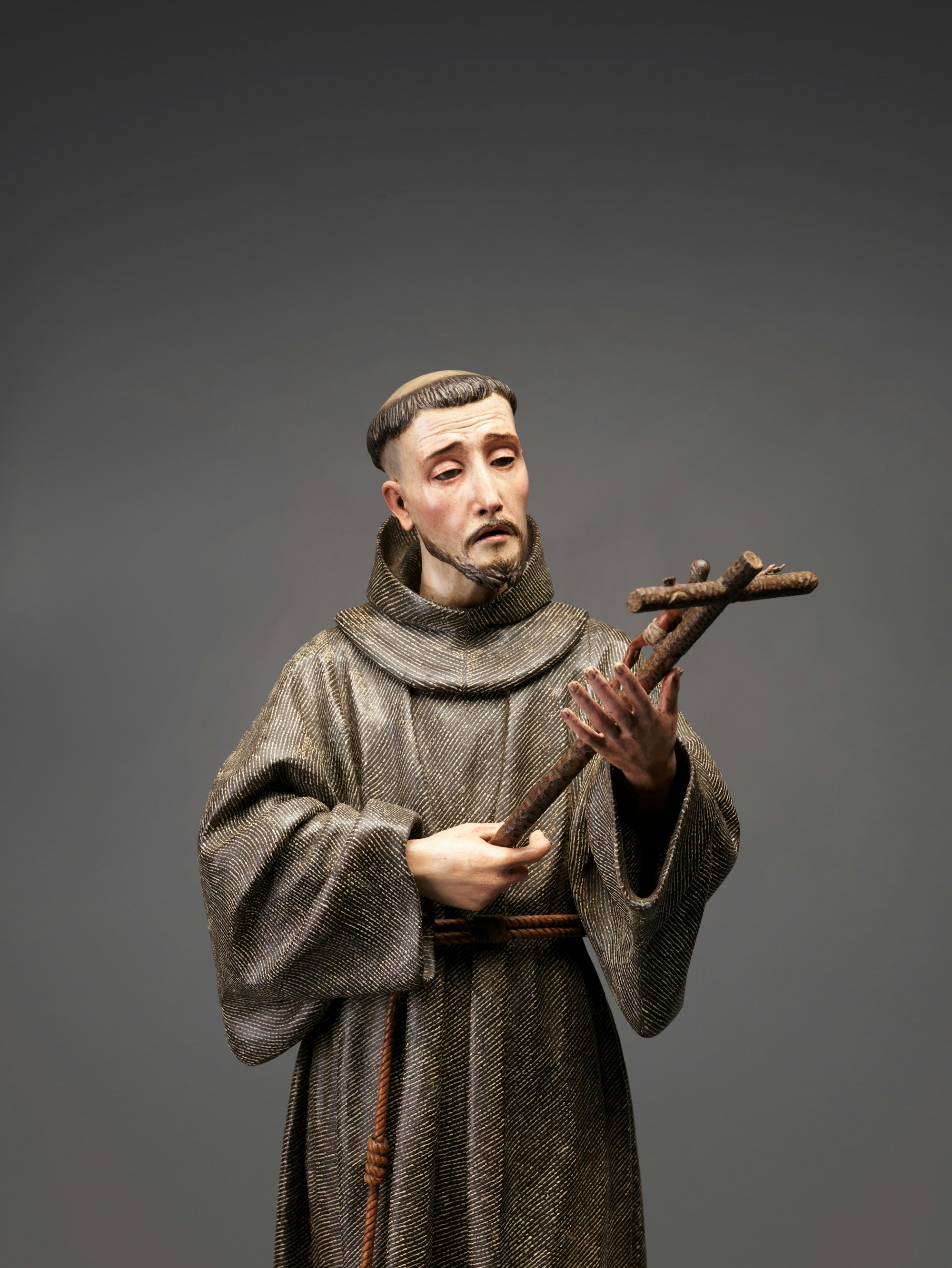 Sculpture of a robed religious figure holding a crucifix.
