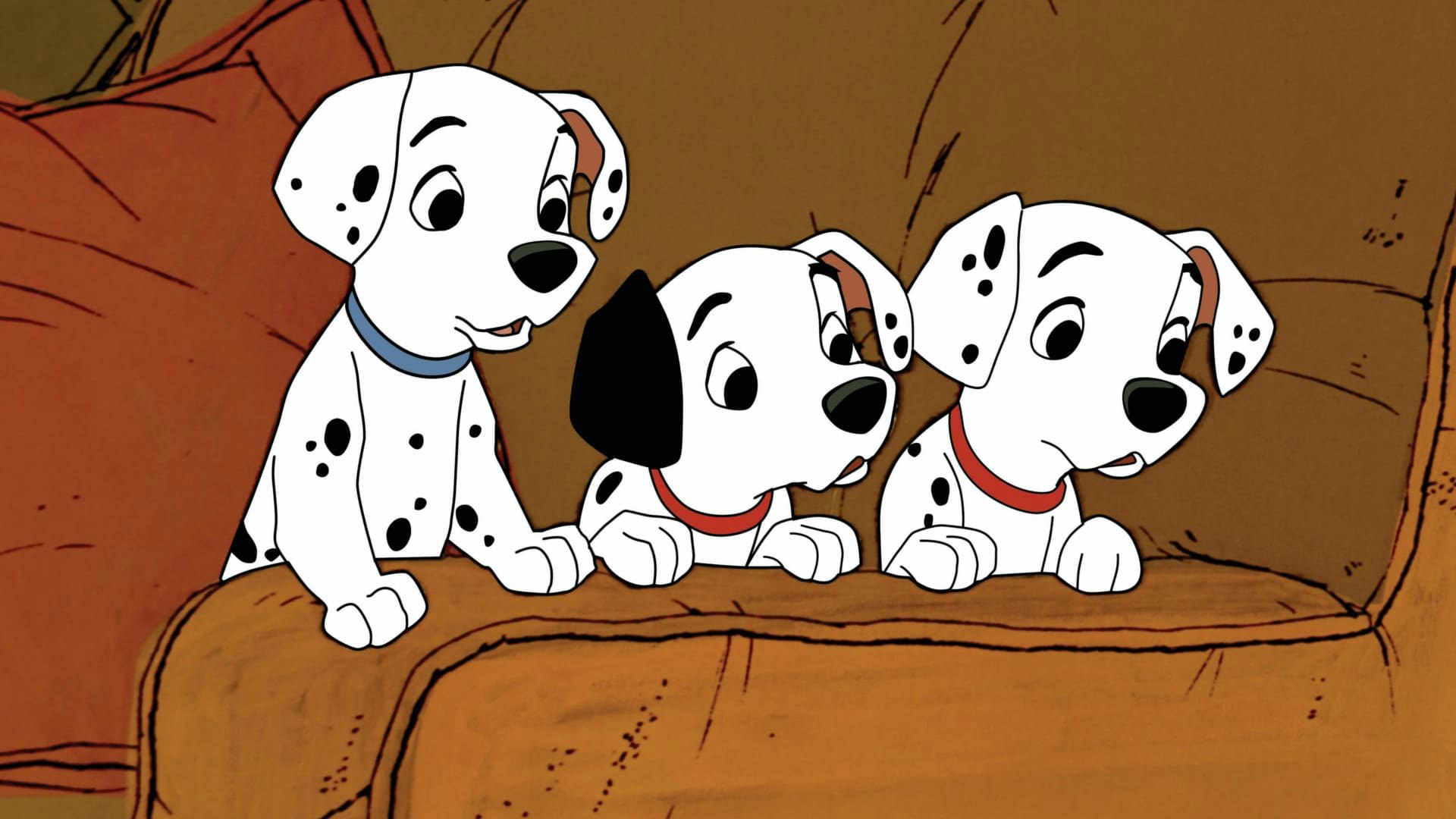 Three Dalmatian puppies peek over the arm of a couch.