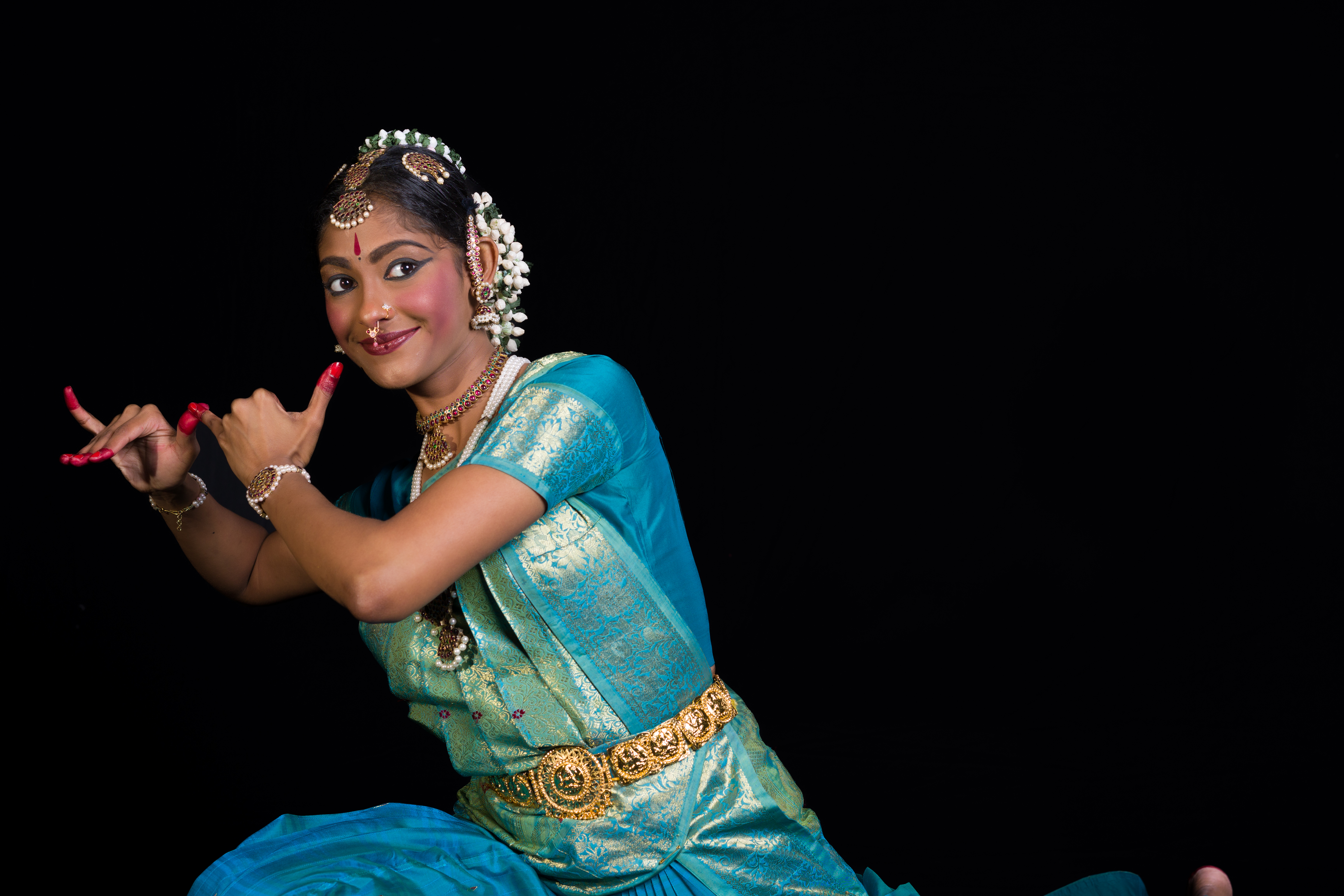 A woman dressed in traditional attire, performing a classical dance on stage.