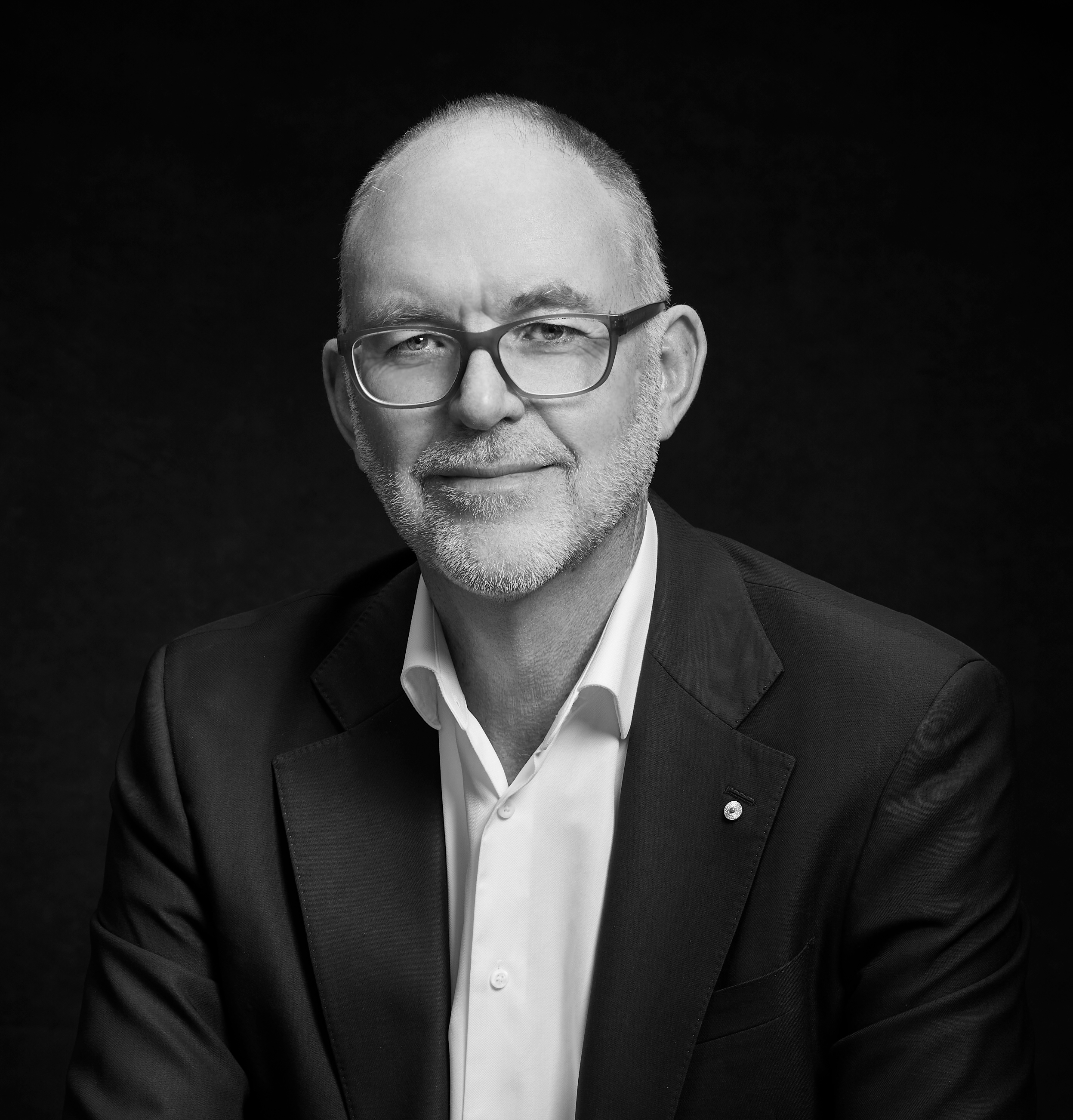 A person with short hair and a beard wearing glasses