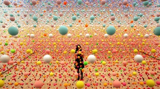 A room filled with colourful spheres suspended midair, with a person standing among them