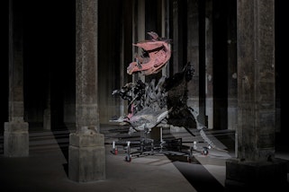 A metallic sculpture in a dimly lit space with pillars.