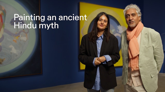 A woman and man standing in front of large artworks.