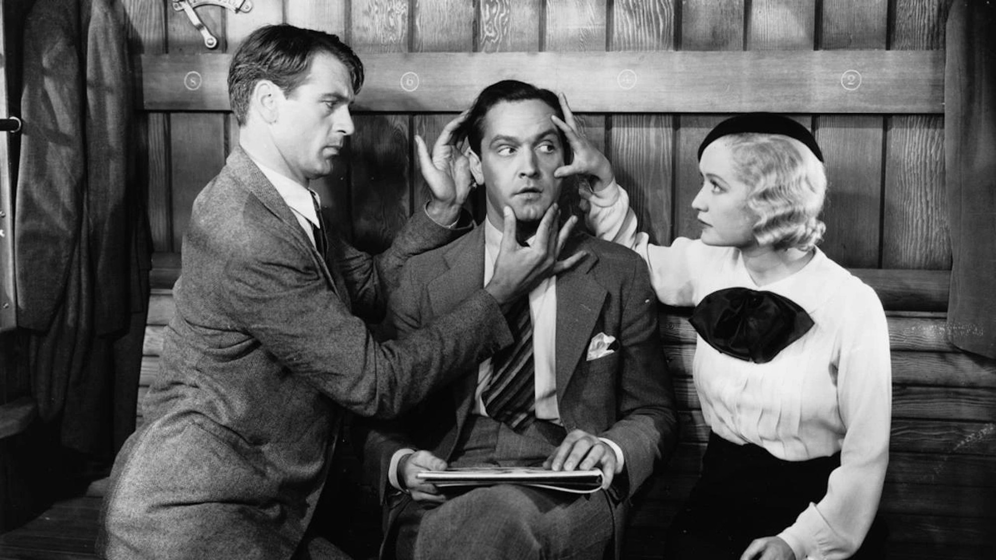 Film still showing two people touching a man's head.