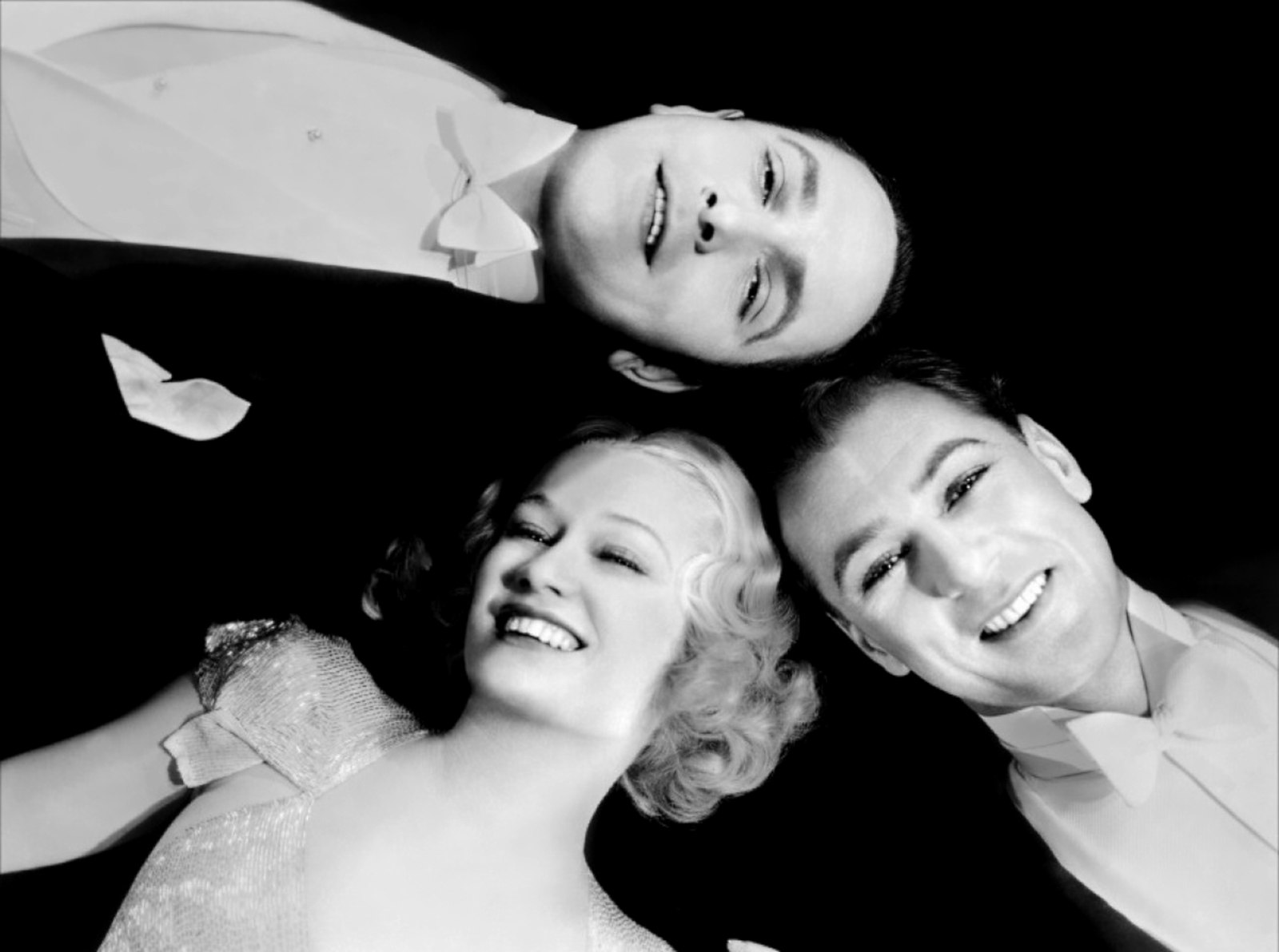 Three people in glamorous attire smiling.