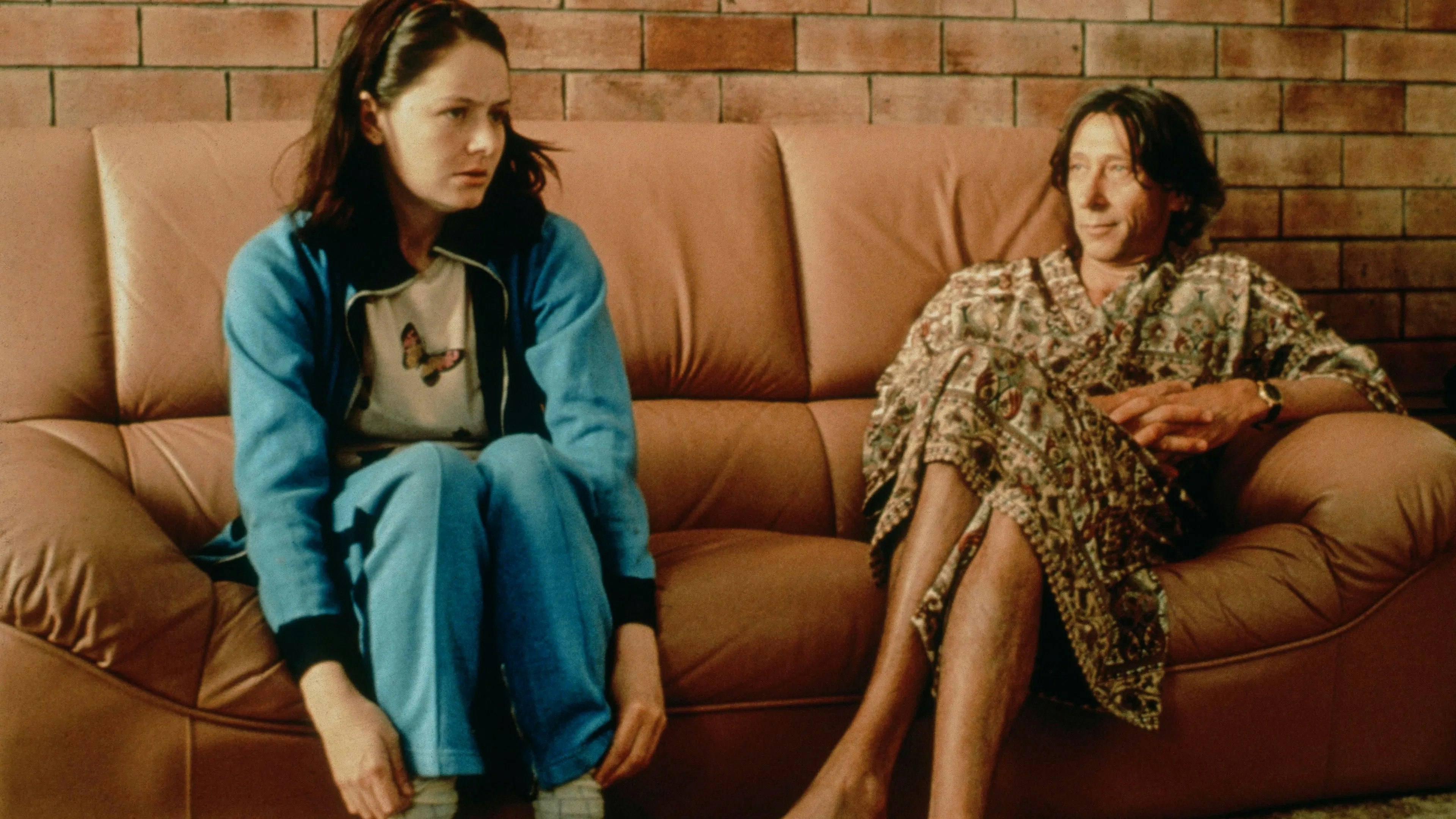A young woman and an older man sitting on a leather couch.