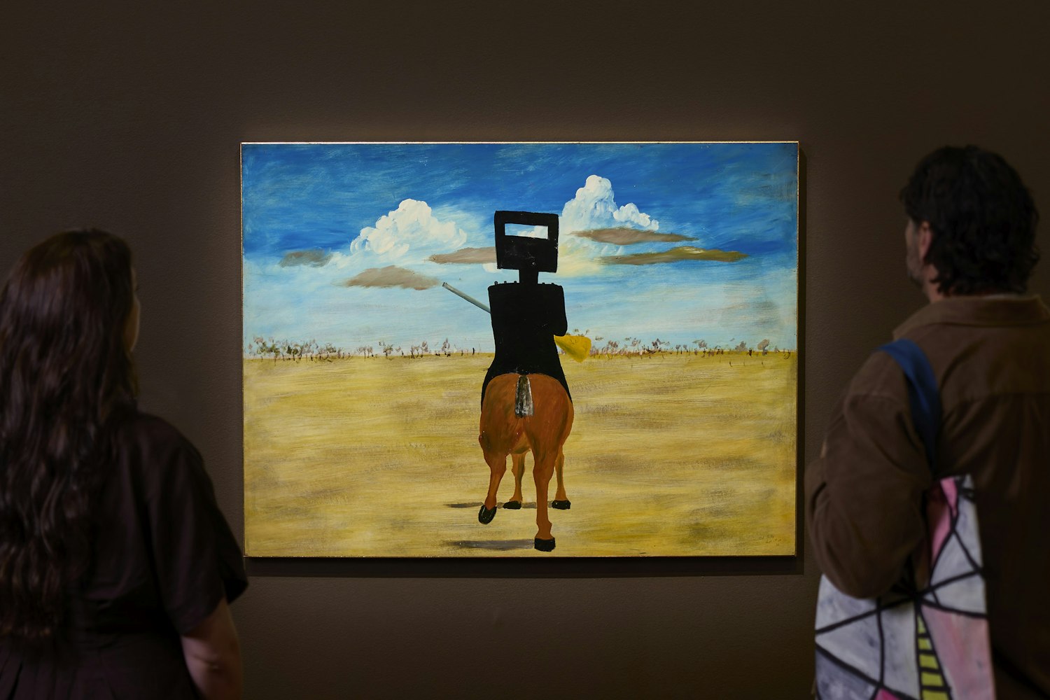 Gallery visitors looking at a portrait painting on display