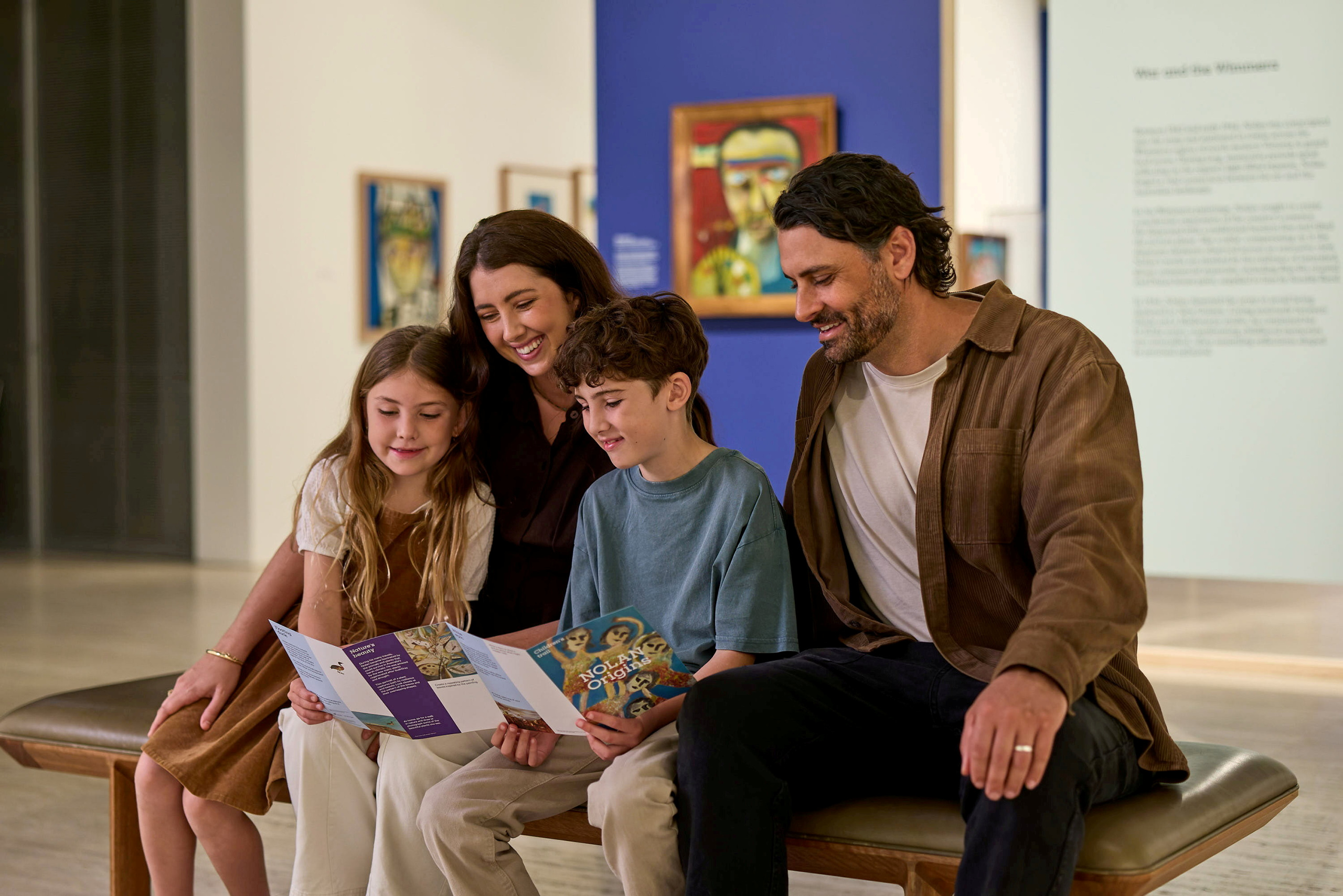 Family of four seated in an exhibition, looking at a brochure.