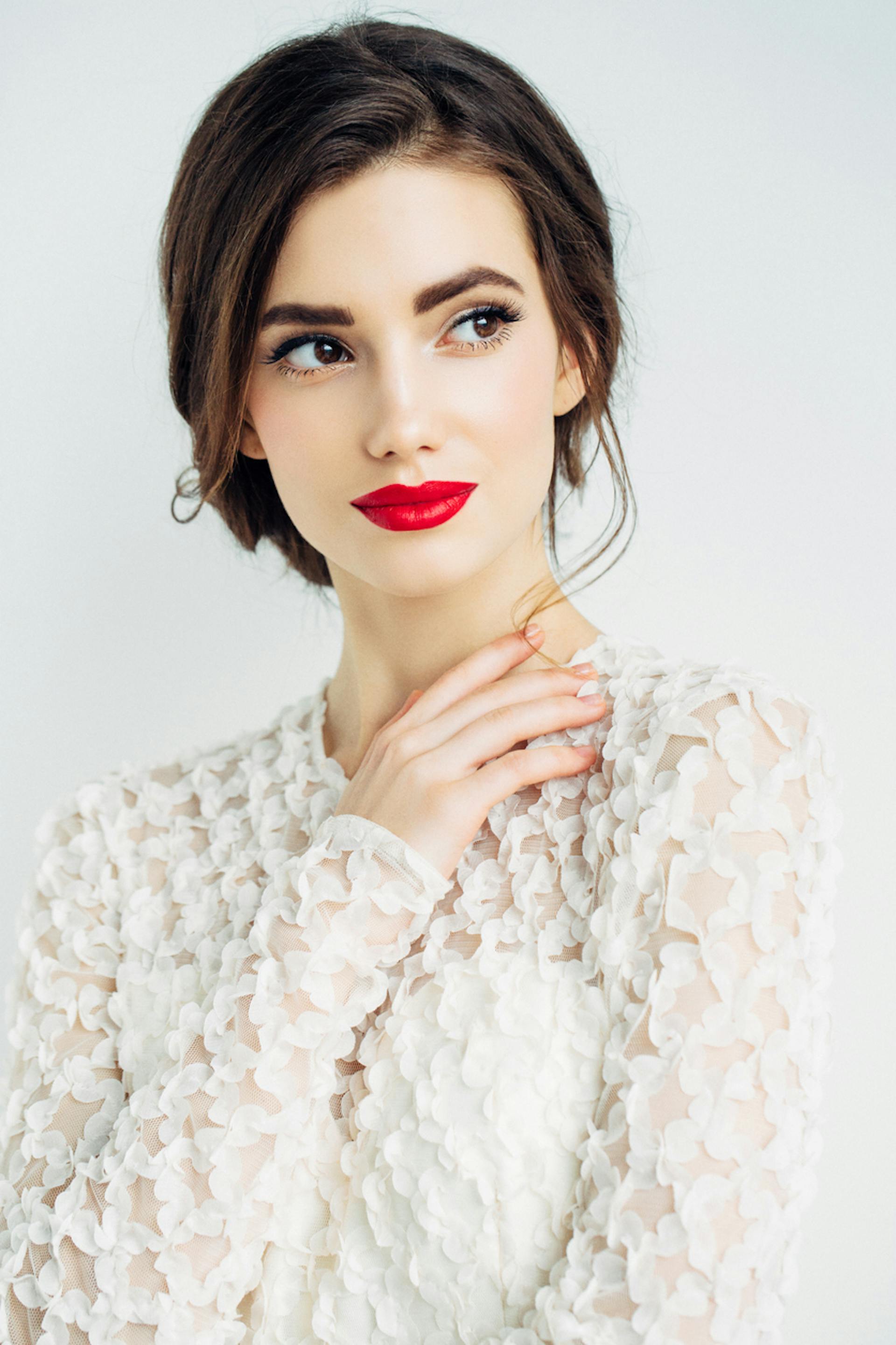 Beautiful woman with brown hair and red lips wearing white.