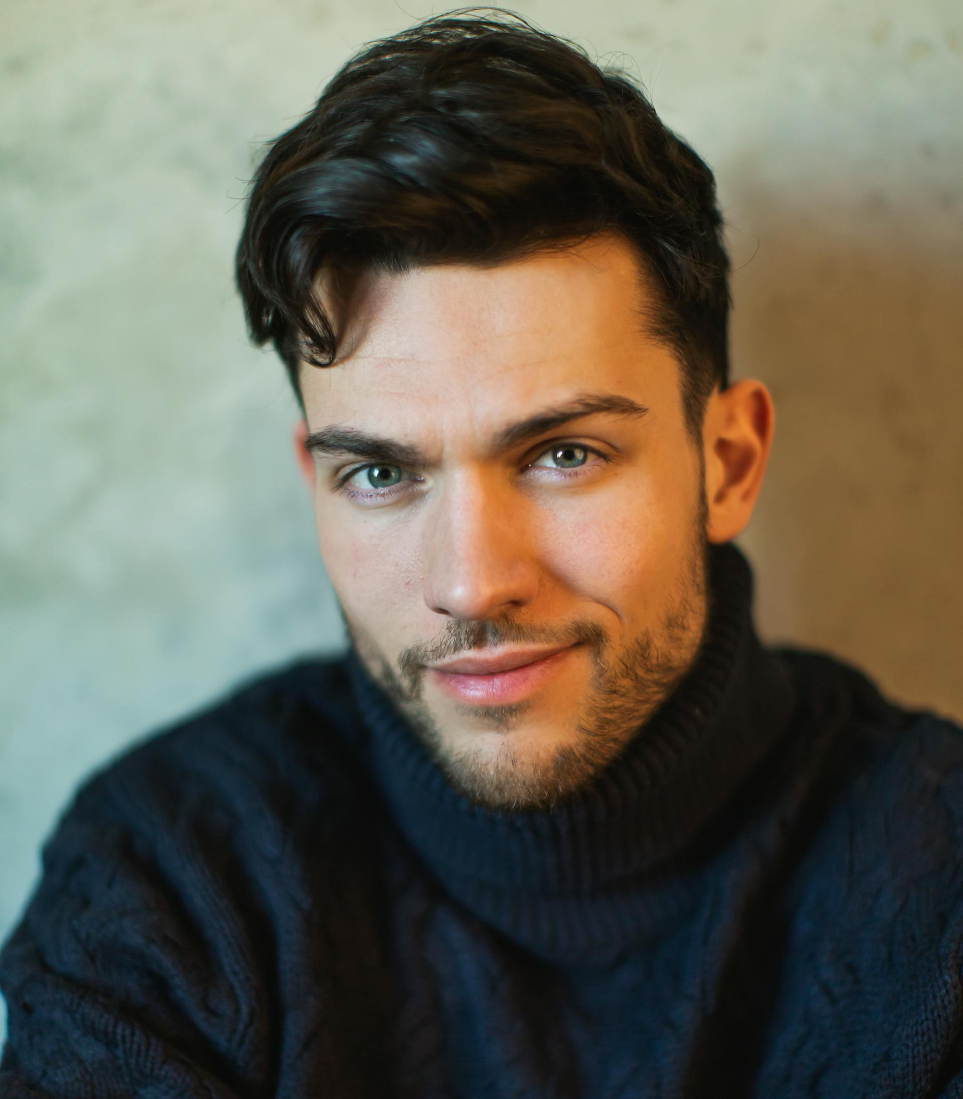 A handsome man in his 30's wearing a turtleneck with a nice thick head of hair