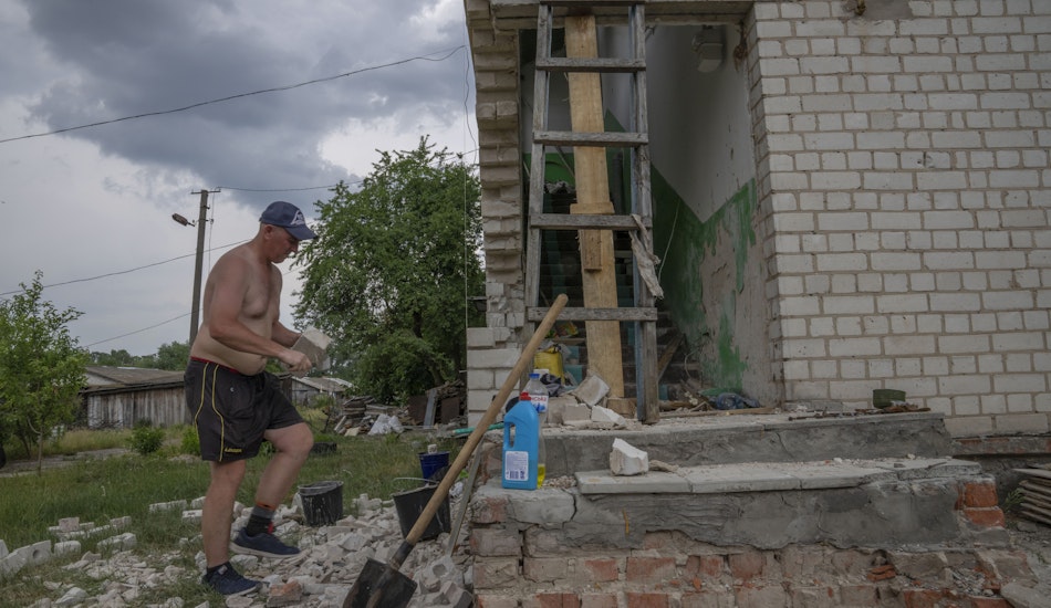 Un bărbat își reconstruiește casa după ce a fost distrusă de ruși, în satul Yahidne, Ucraina