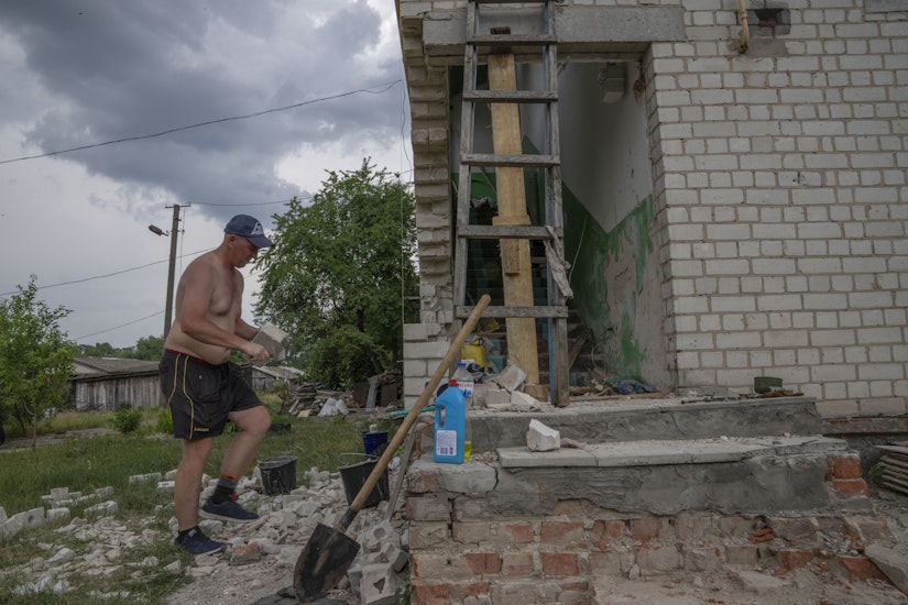 Un bărbat își reconstruiește casa după ce a fost distrusă de ruși, în satul Yahidne, Ucraina