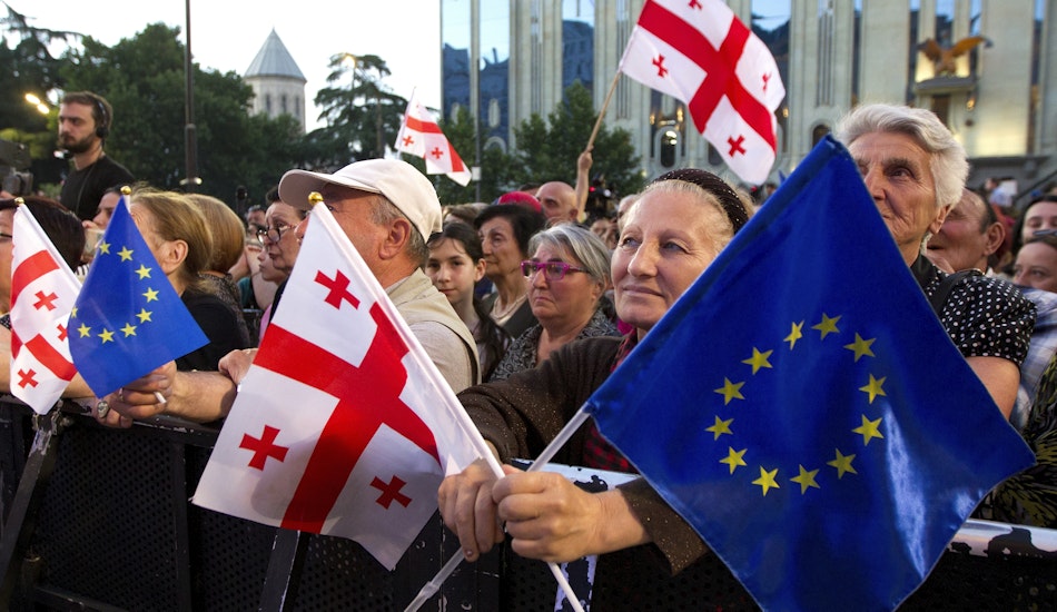 Manifestanți georgieni în fața Parlamentului georgian din Tbilisi cu steaguri naționale georgiene și ale UE 
