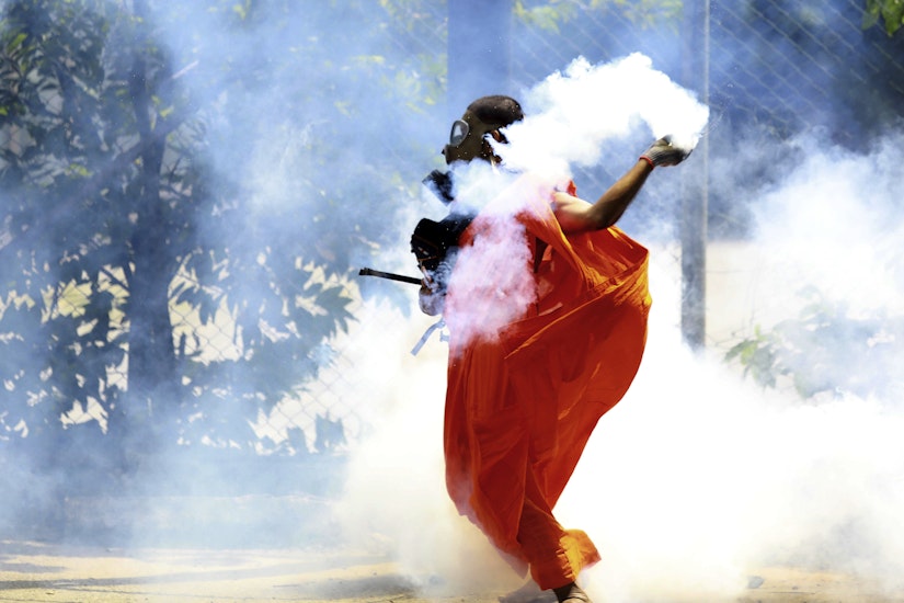 Un bărbat aruncă înapoi un proiectil cu gaz lacrimogen după ce a fost lansat de poliție pentru a dispersa protestatarii din Colombo, Sri Lanka