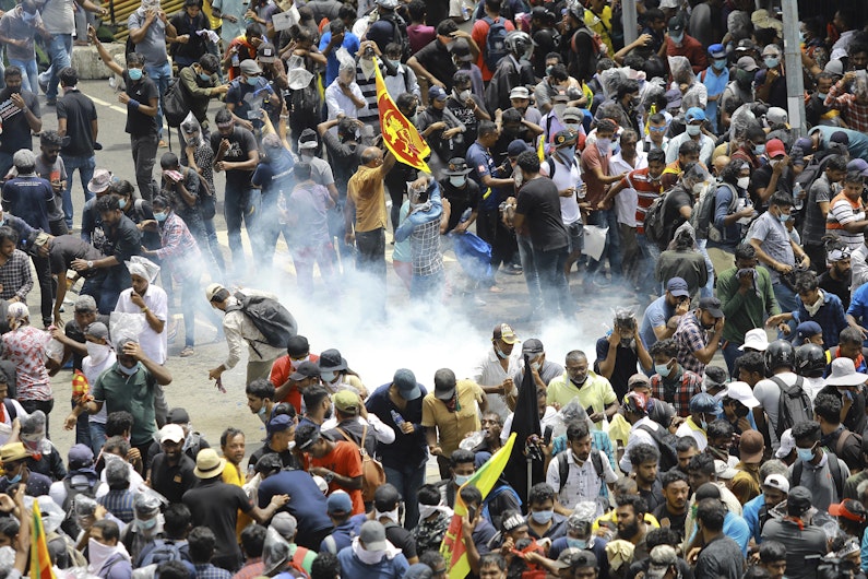 Protestatarii reacționează în timp ce un proiectil cu gaze lacrimogene lansat de poliție aterizează lângă ei în Colombo