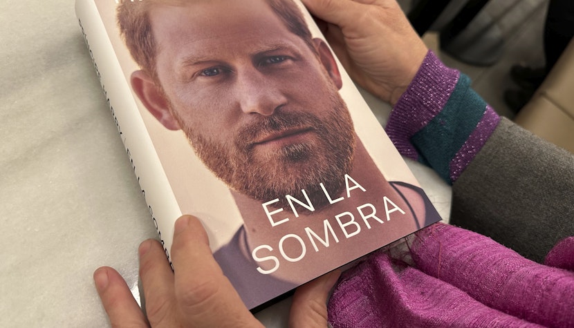 O femeie ține în mână un exemplar din „En La Sombra” („În umbră”), traducerea în spaniolă a cărții de memorii a Prințului Harry, „Spare”.