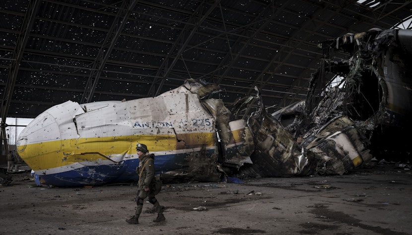 Un militar ucrainean în fața avionul Antonov An-225, distrus în timpul luptelor dintre forțele ruse și ucrainene