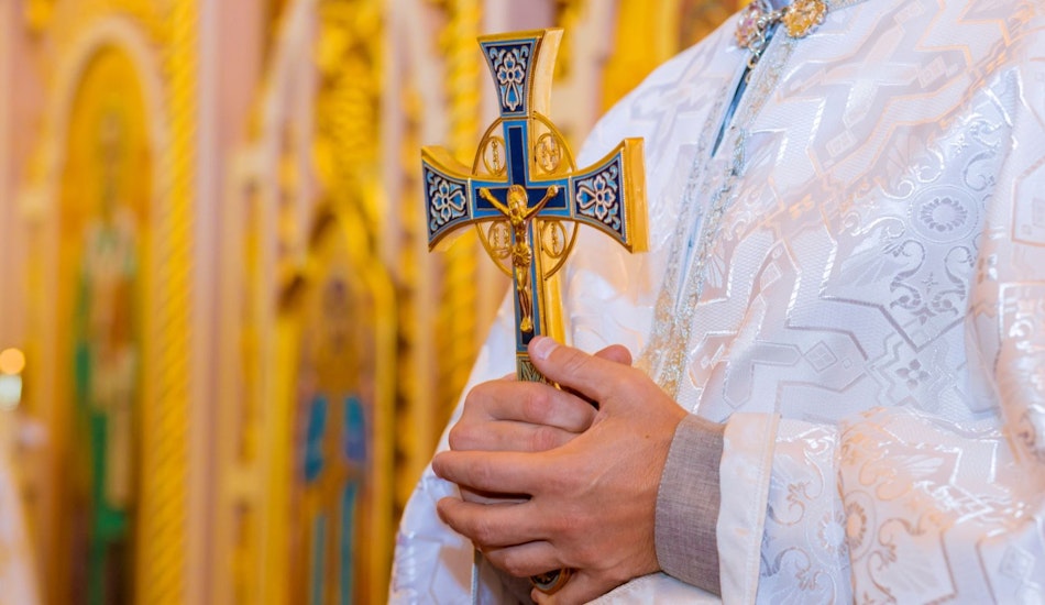 Un preot care ține în mână o cruce