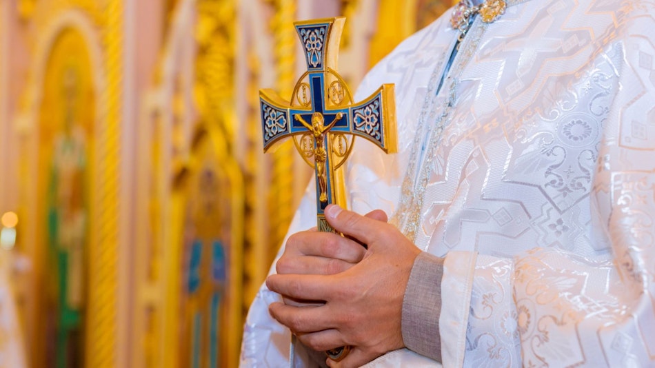 Un preot care ține în mână o cruce