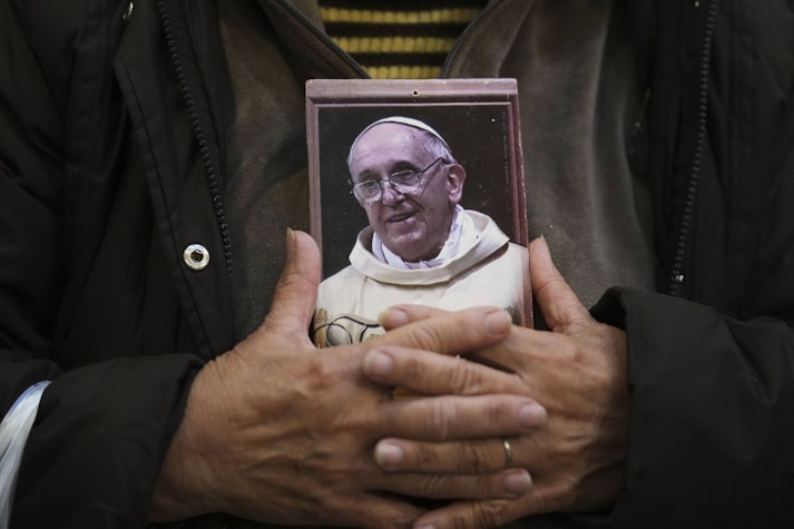 fotografia papei francisc tinuta în mâini de un credincios