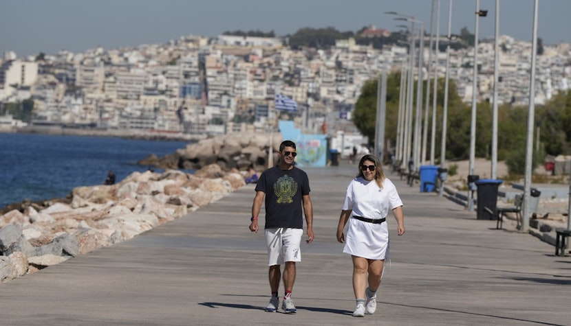 Grecia Doi turiști plimbându-se, într-o localitate din Grecia