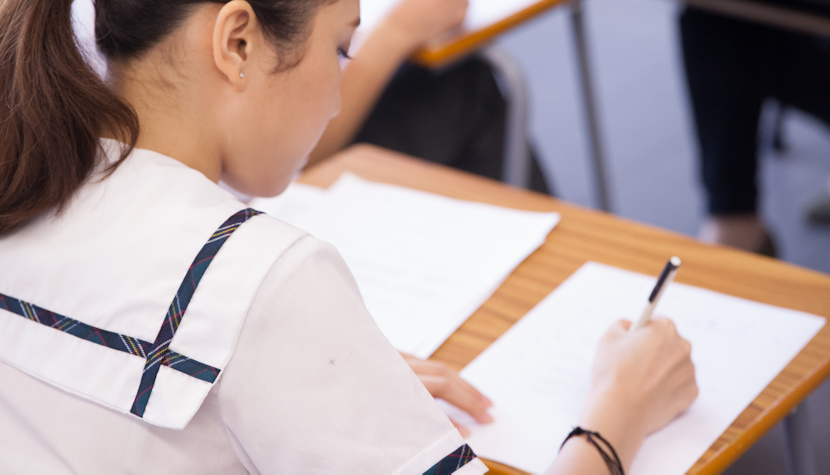 Probele scrise la bacalaureat durează trei ore o elevă scrie pe o foaie în timpul unui examen