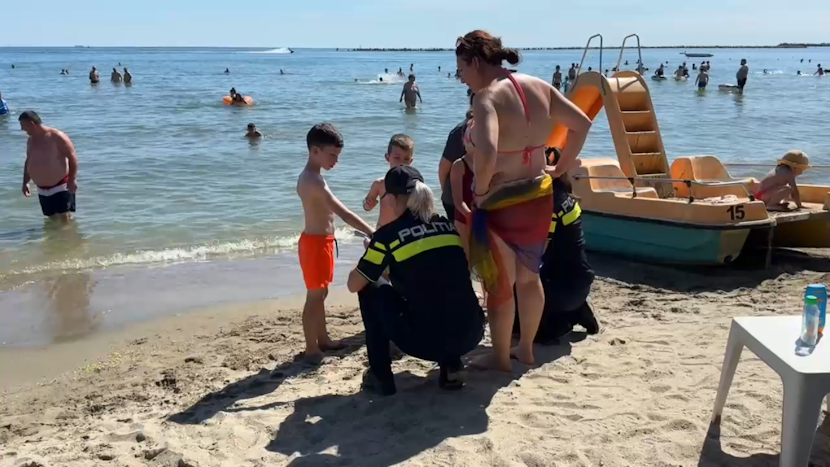 Agenți de poliție discută cu copiii și cu părinții pe plajă.
